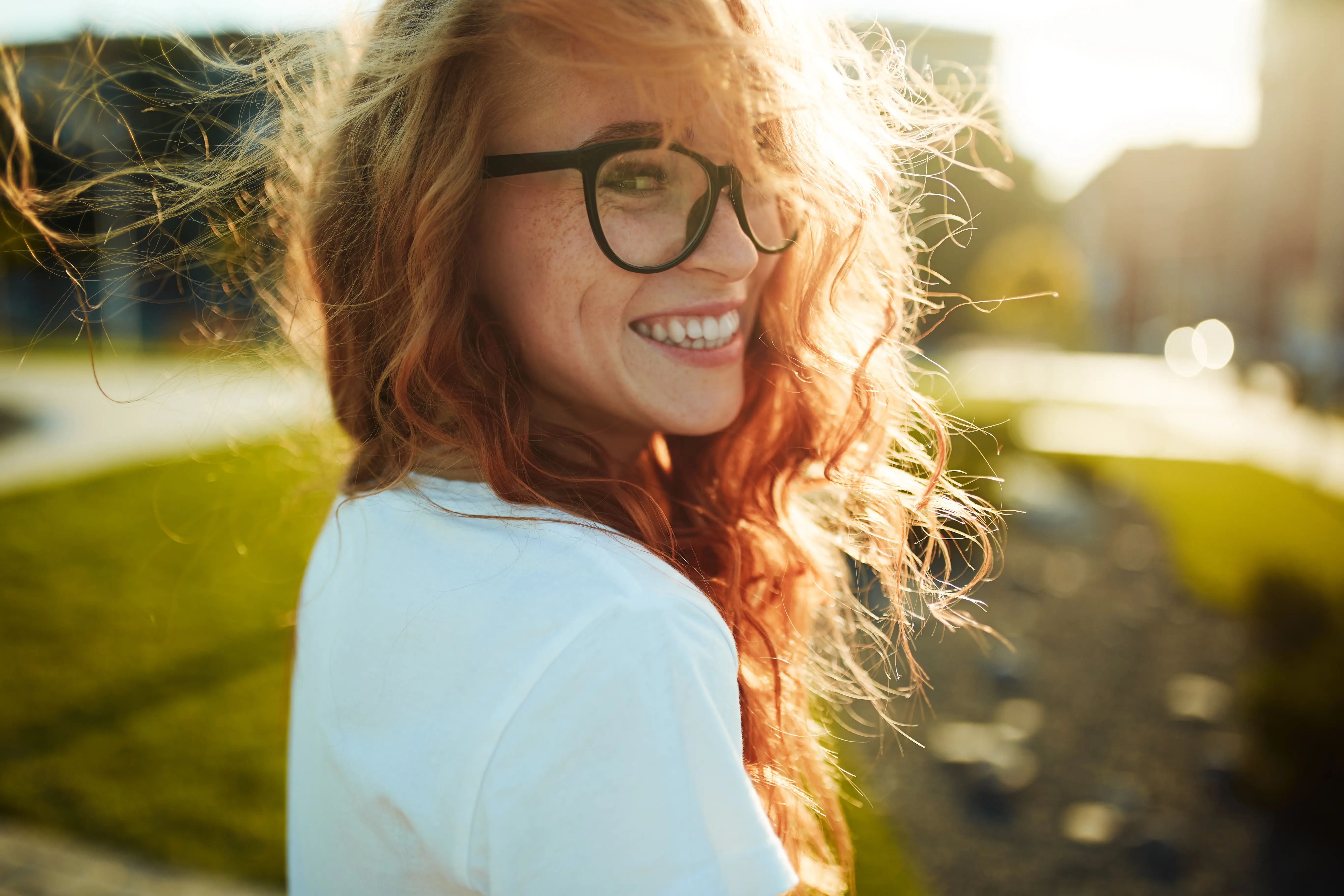A woman with red hair and glasses smiling.