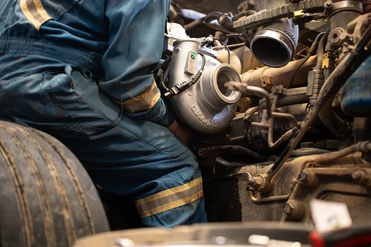 Turbo repair technician servicing a BorgWarner turbocharger inside a heavy-duty truck engine bay.