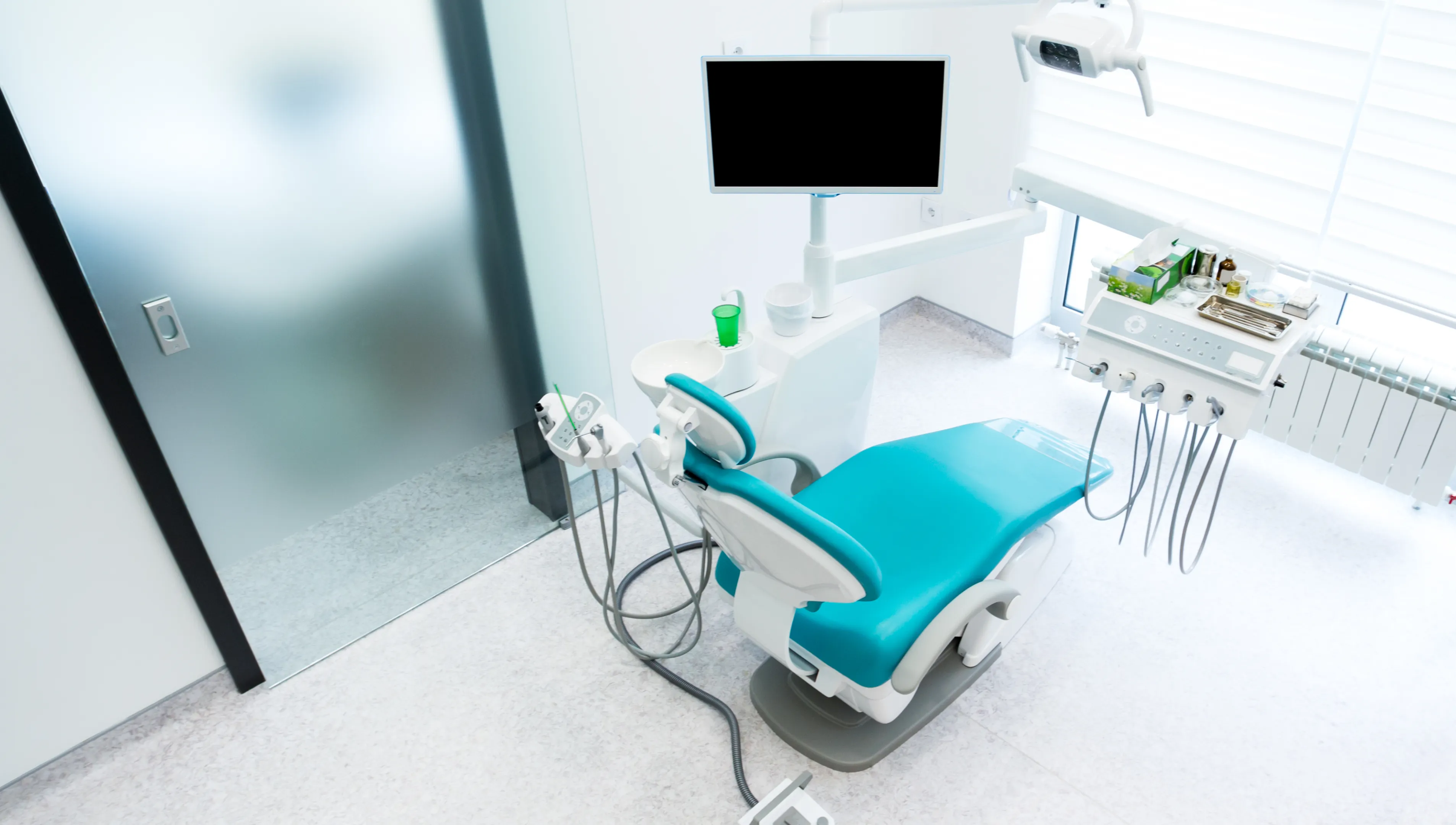 A hospital room with a monitor, chair, and other medical equipment.