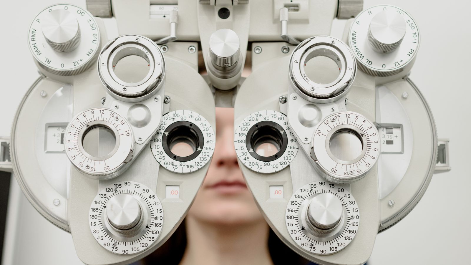 Optometrist adjusting a phoropter during an eye exam in a modern exam lane