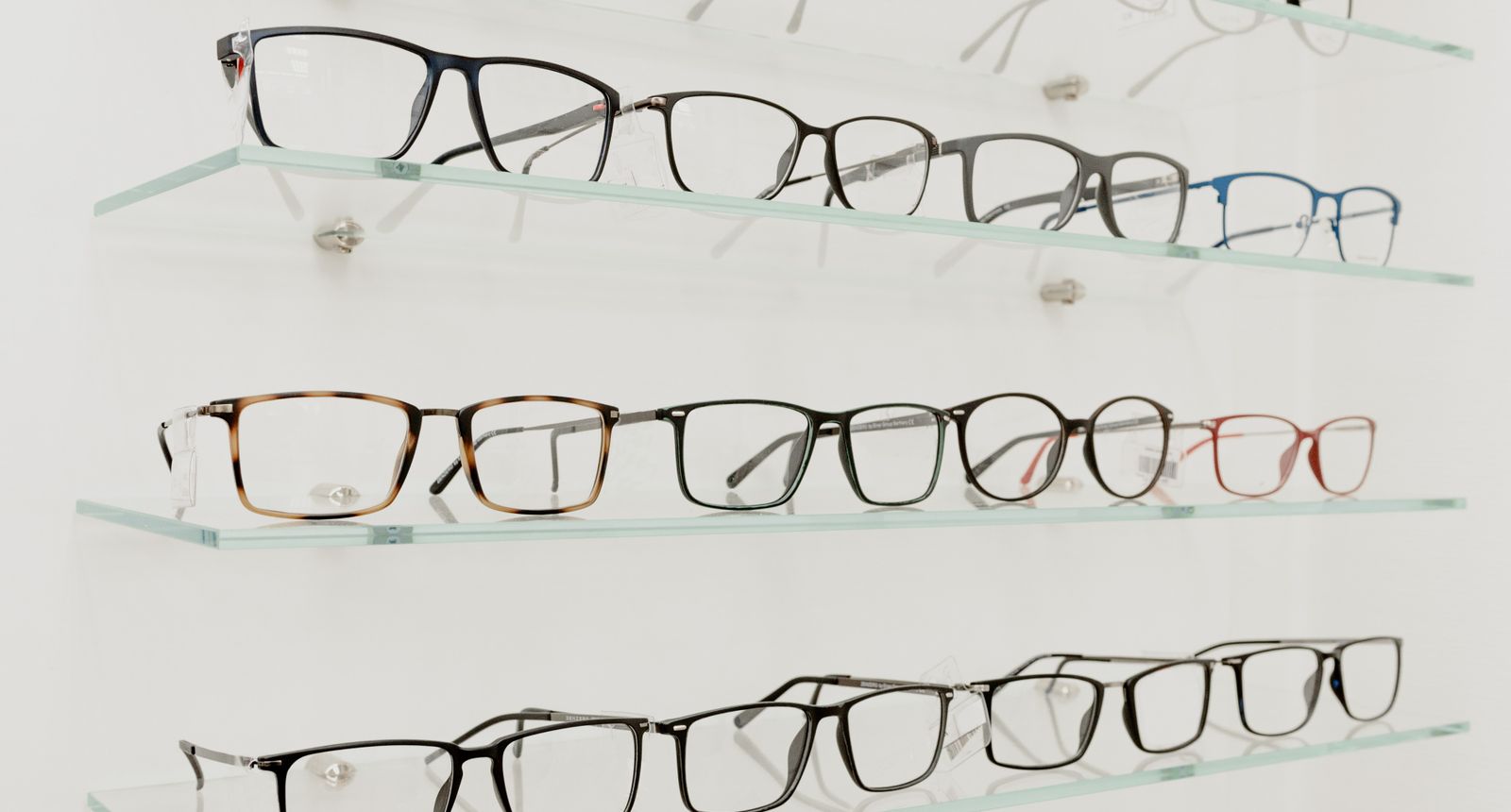 Rows of eyeglasses displayed on glass shelves in an optical dispensary