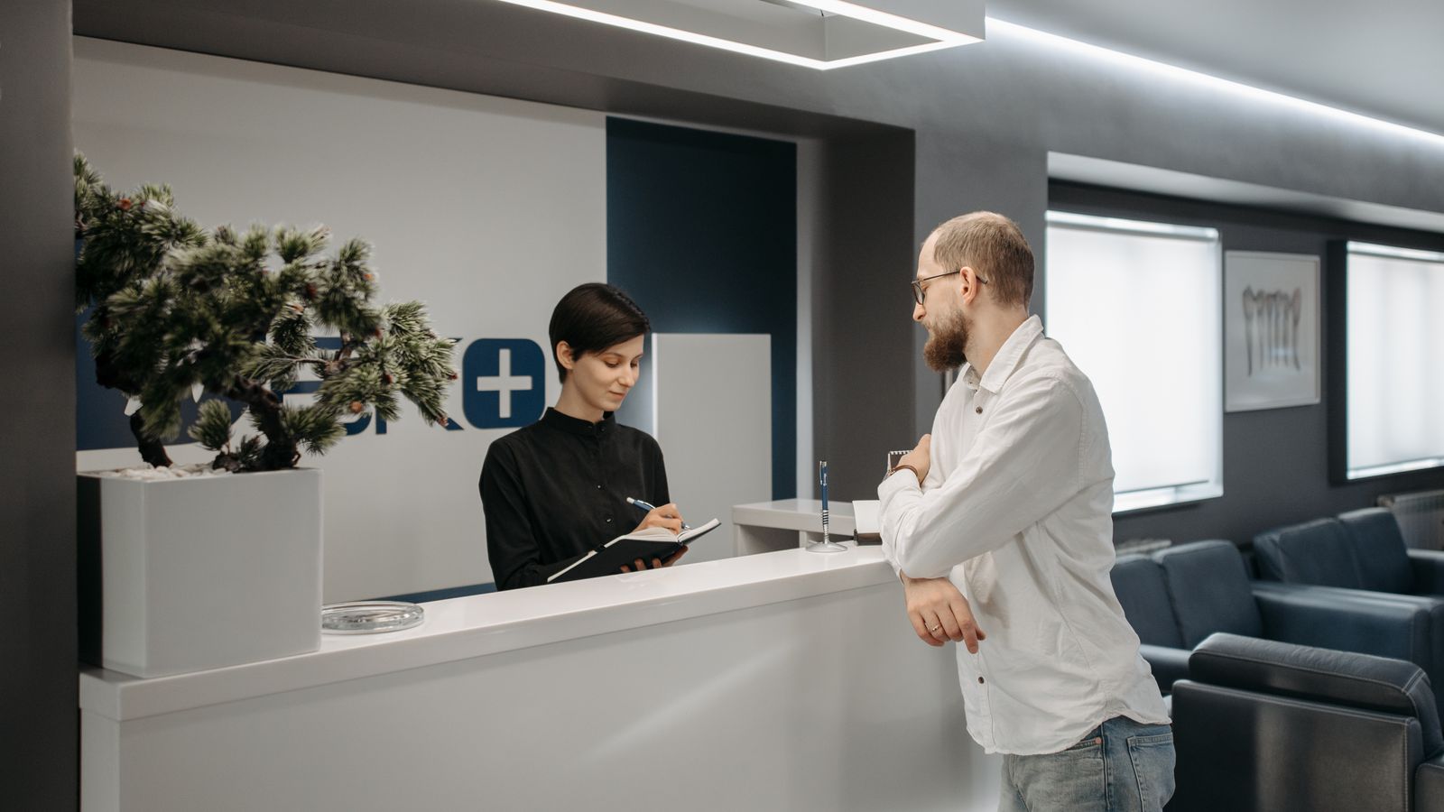 Patient checking in with a receptionist at a modern clinic front desk