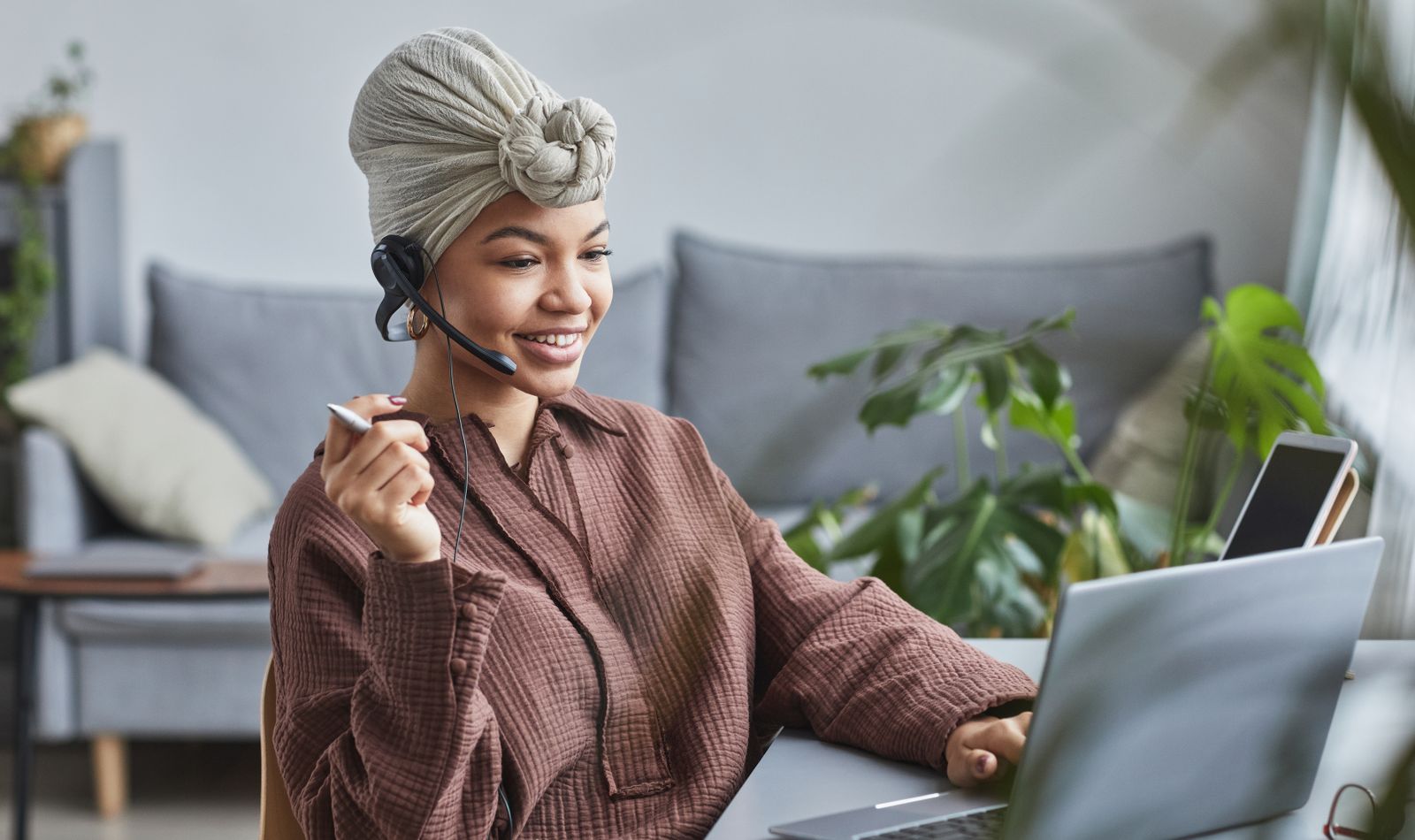 Remote assistant wearing a headset working on a laptop from a home office