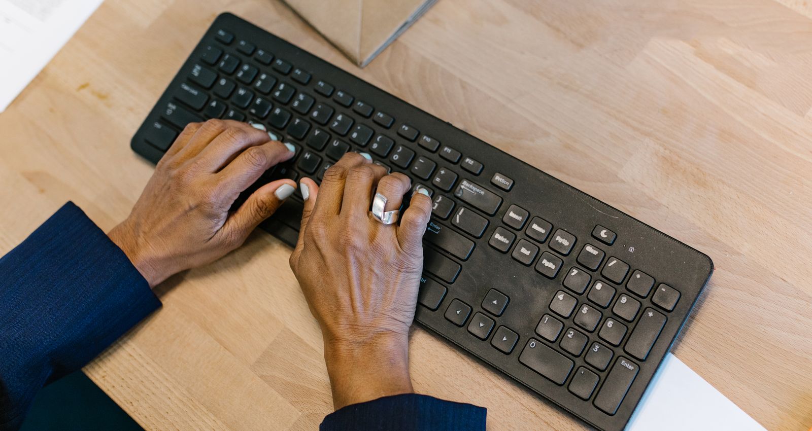Overhead view of hands typing on a keyboard at an office desk