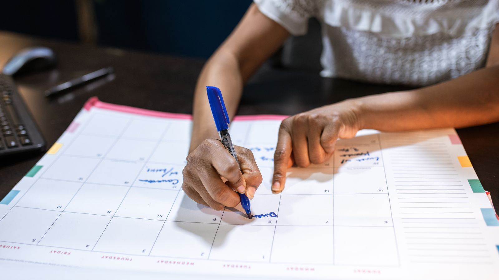 Staff member marking appointment dates on a desk calendar