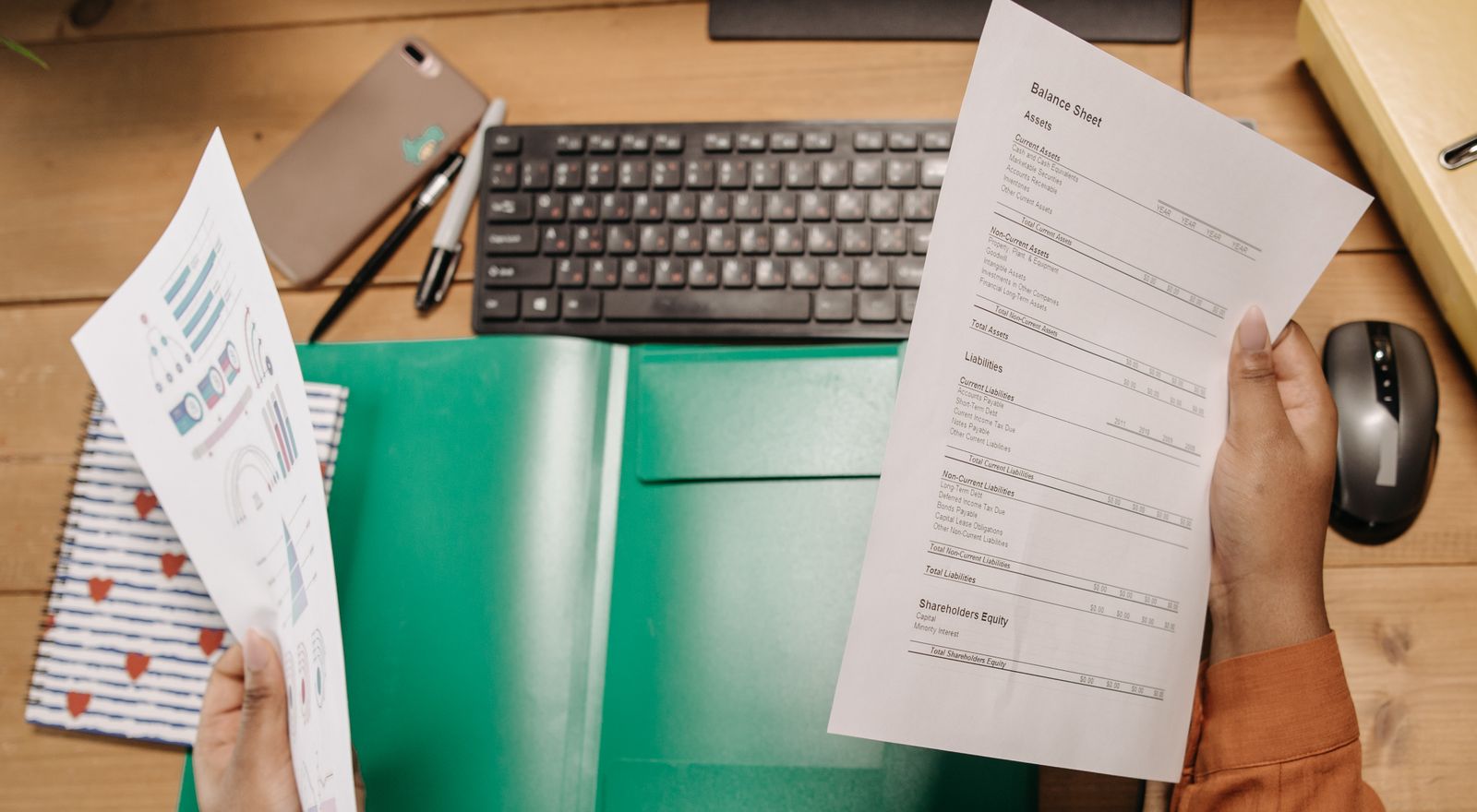 Hands comparing two benefit documents side by side over a desk