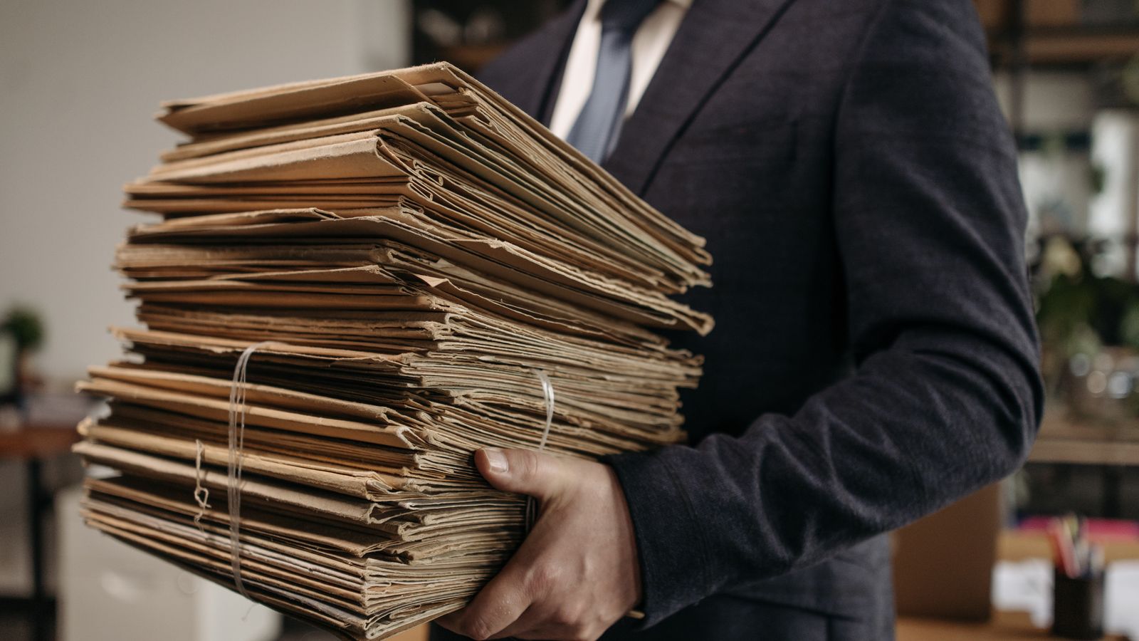 Professional carrying a large stack of aged file folders