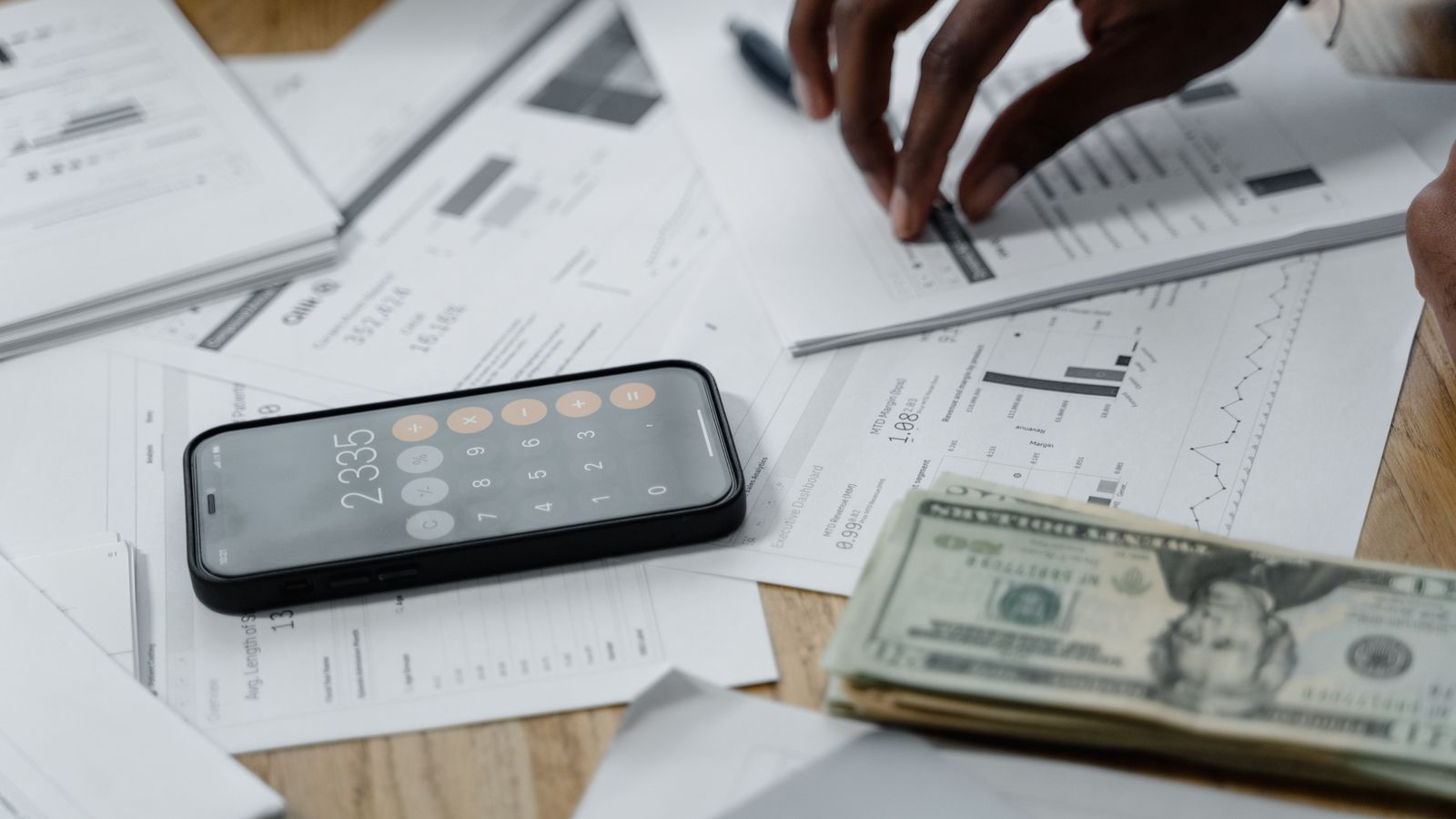 Hands working through billing reports with calculator and statements