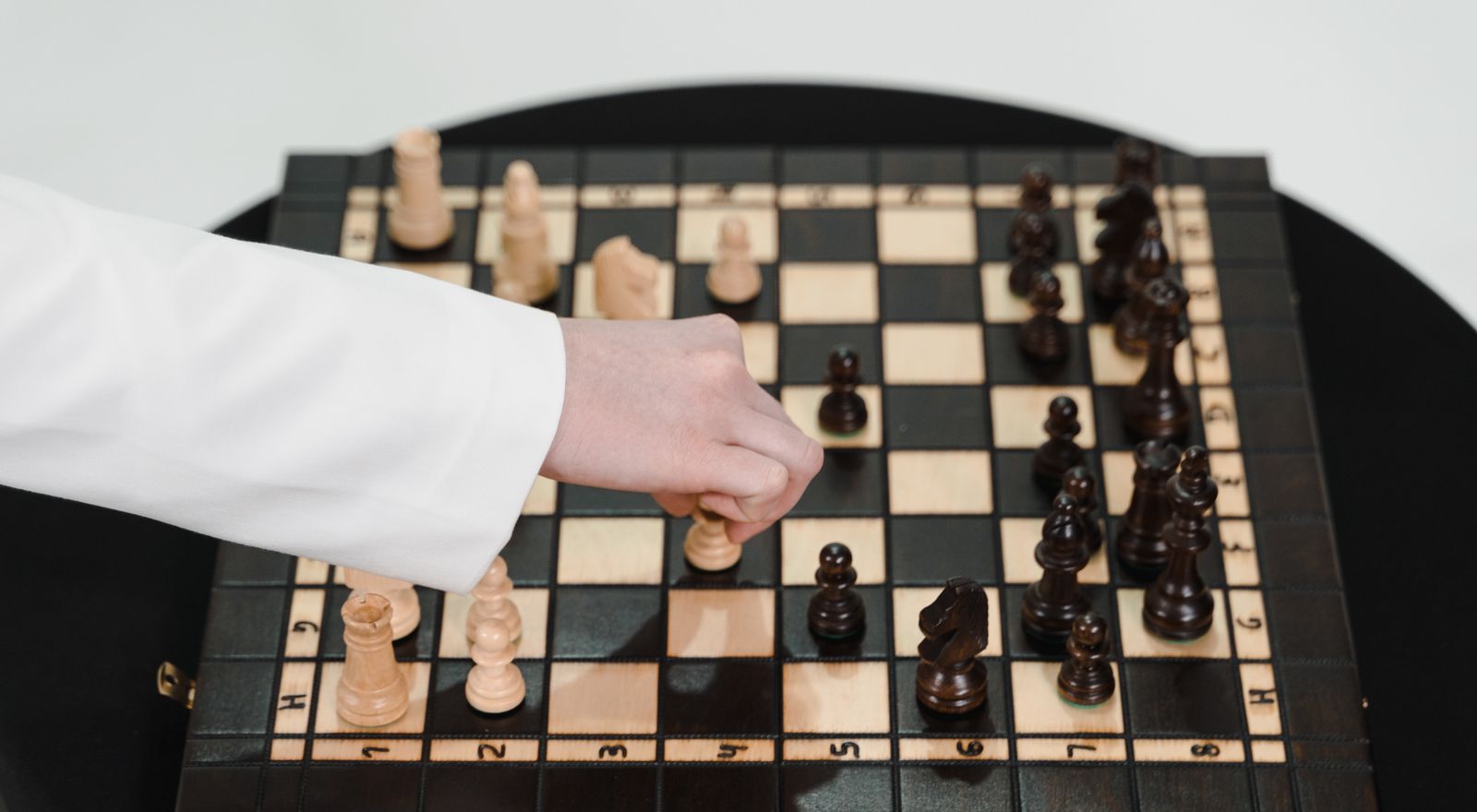 Hand moving a piece on a wooden chessboard