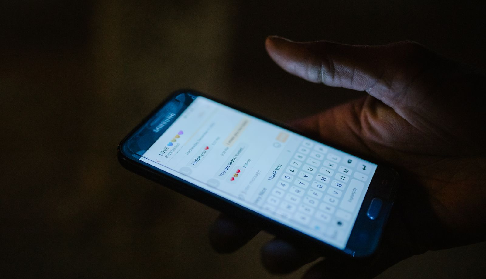Hand holding a smartphone with a messaging conversation open