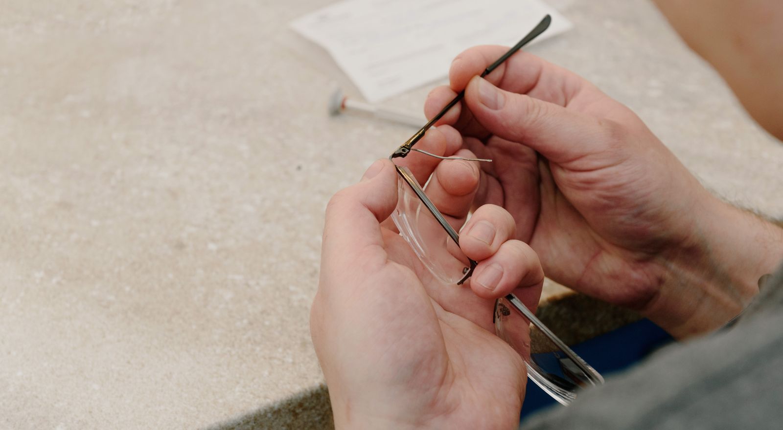 Optician's hands adjusting the temple of an eyeglass frame