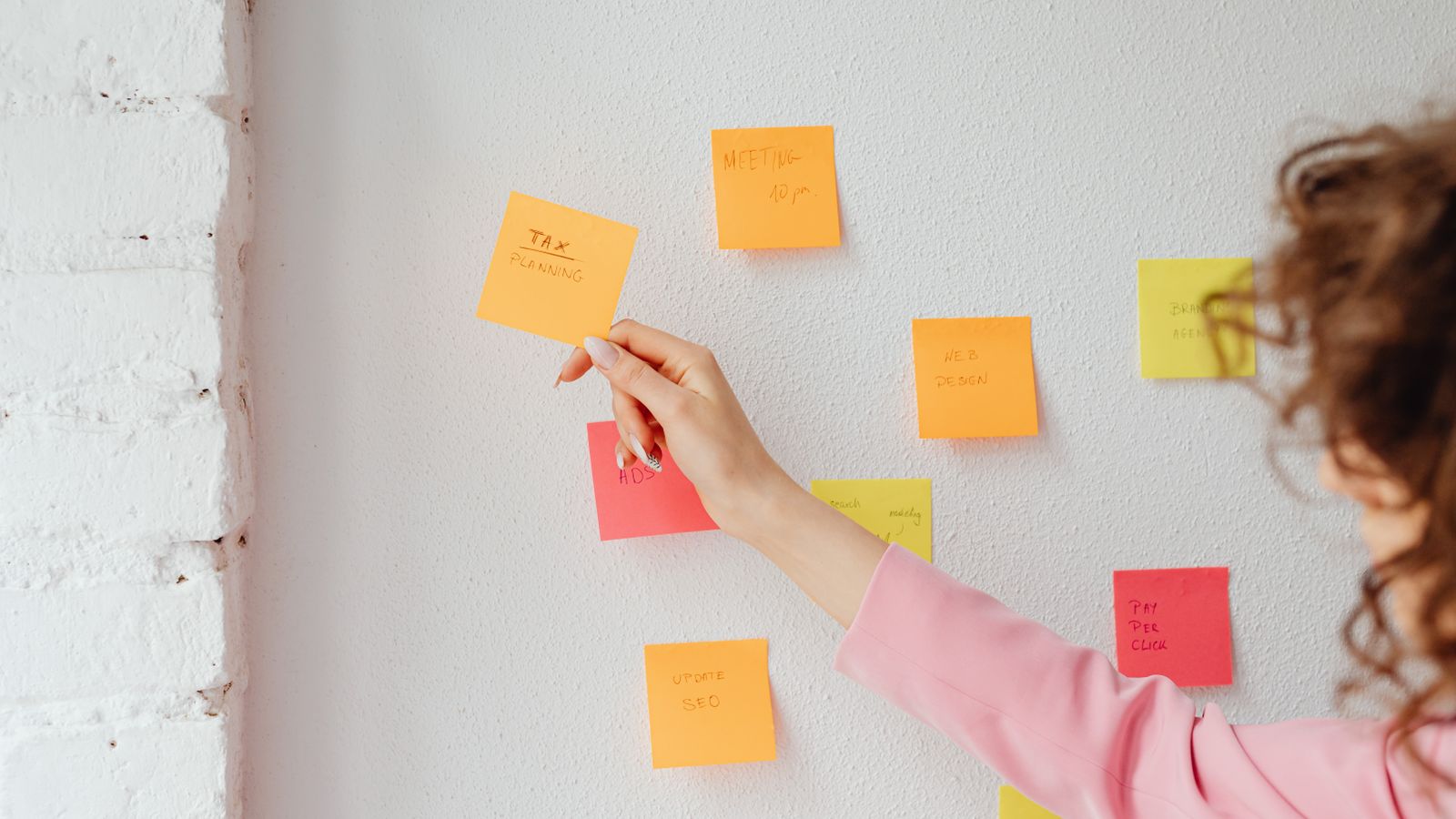 Office manager organizing duties with sticky notes on a wall