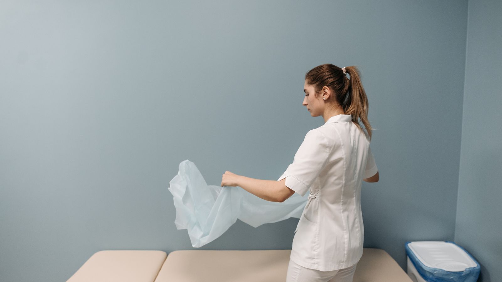 Clinical assistant preparing an exam room between patients