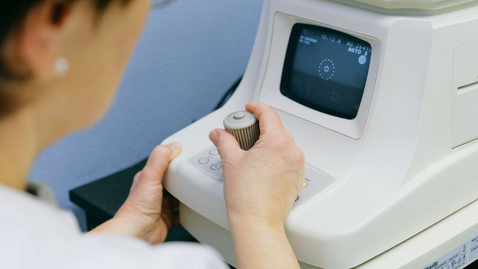 Optometric technician operating an eye examination machine