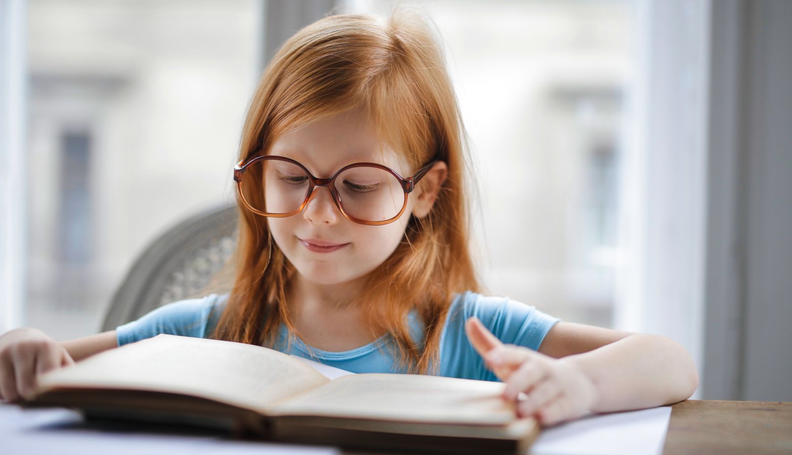 Young child wearing glasses while reading a book