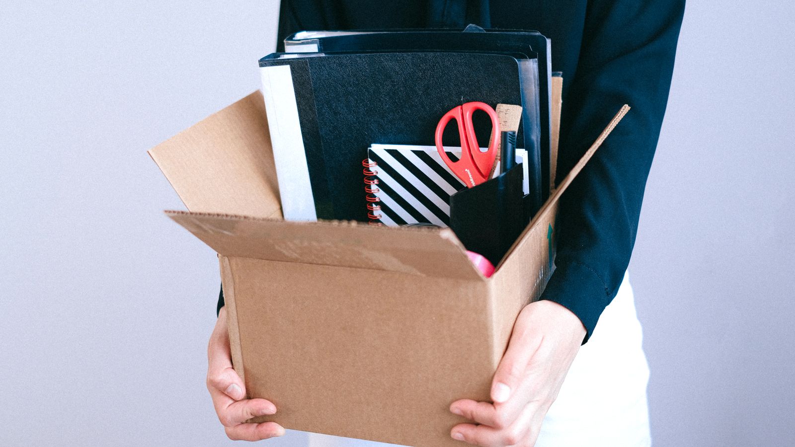 Departing employee carrying a box of desk belongings