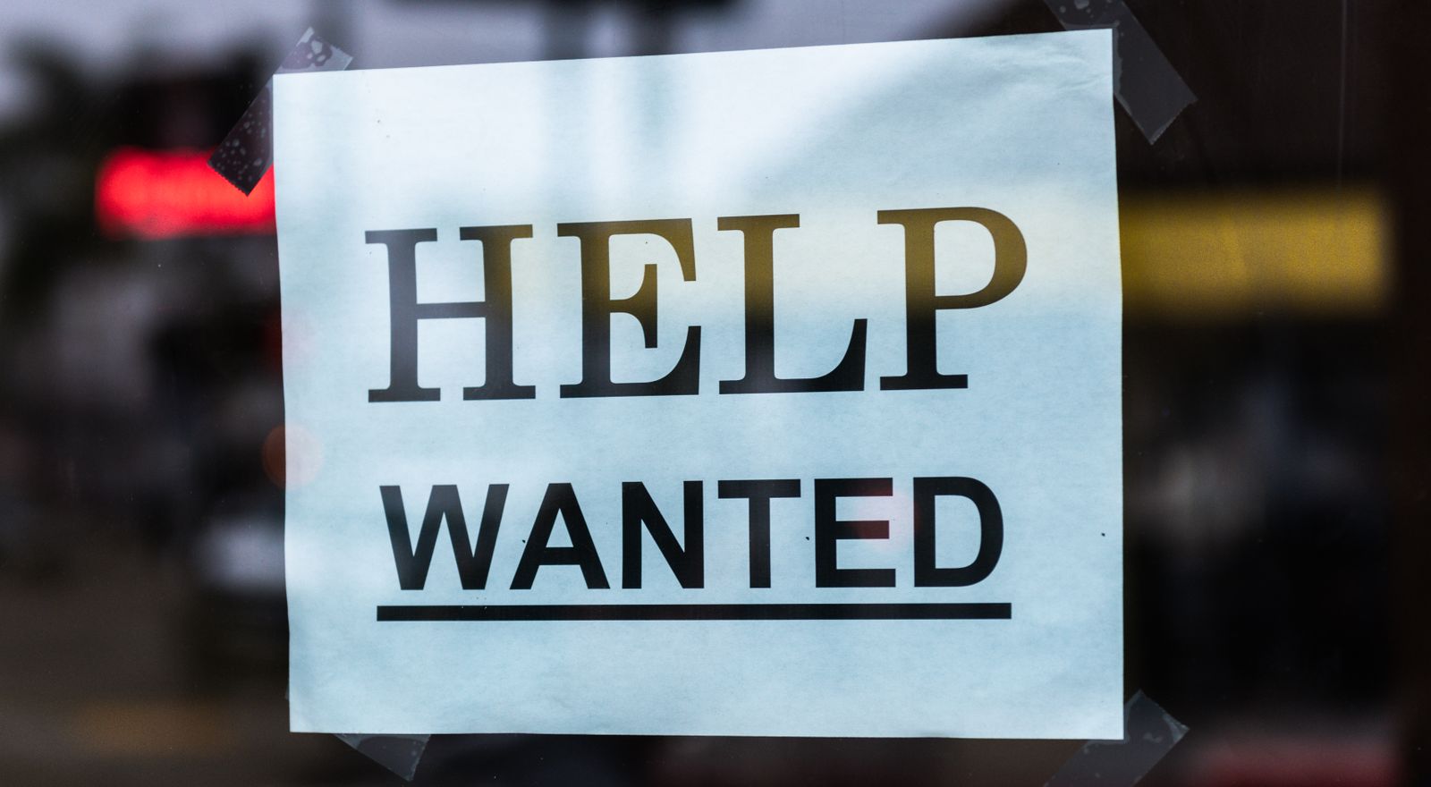 Help wanted sign taped inside a storefront window