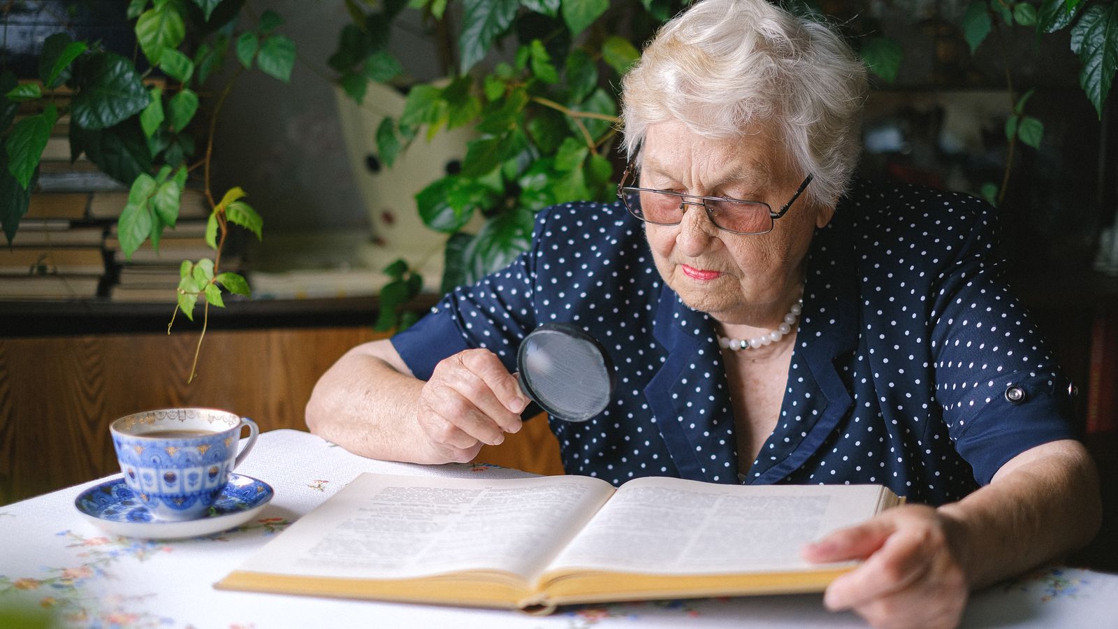 Elderly reader using a magnifier over a book
