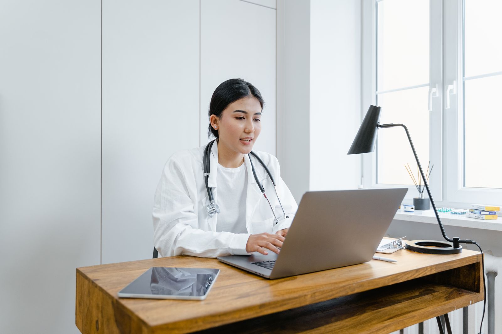 Doctor preparing correspondence and patient reports on a laptop