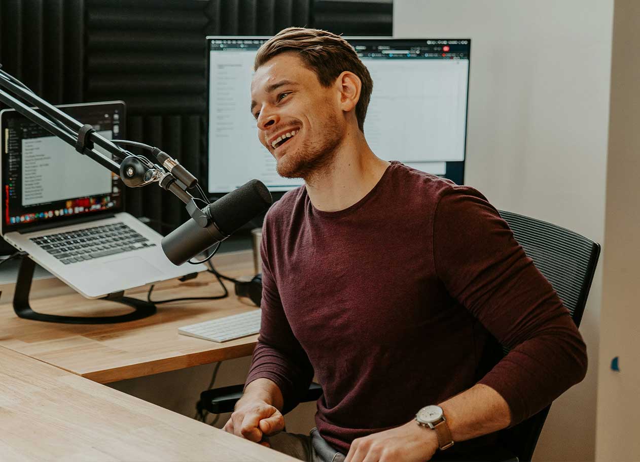 Man sitting in recording booth talking into a microphone