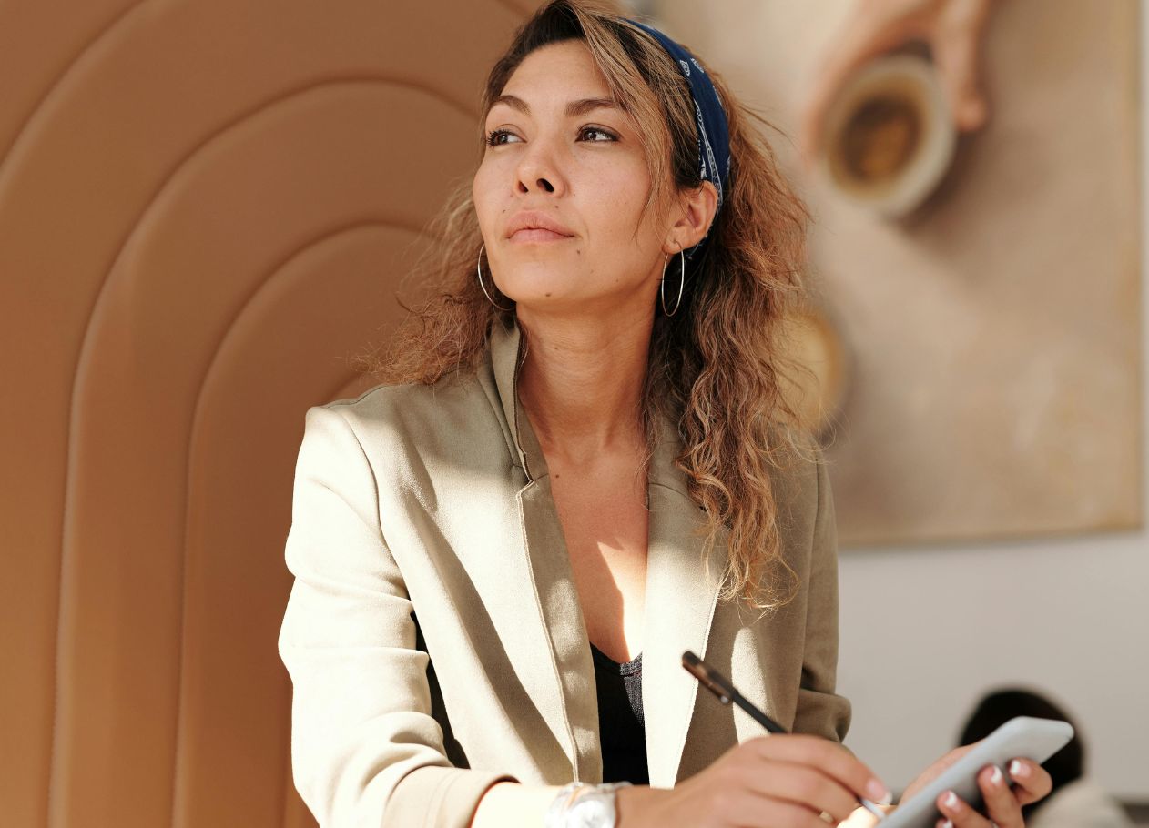 woman in coffee shop looking around while working on phone