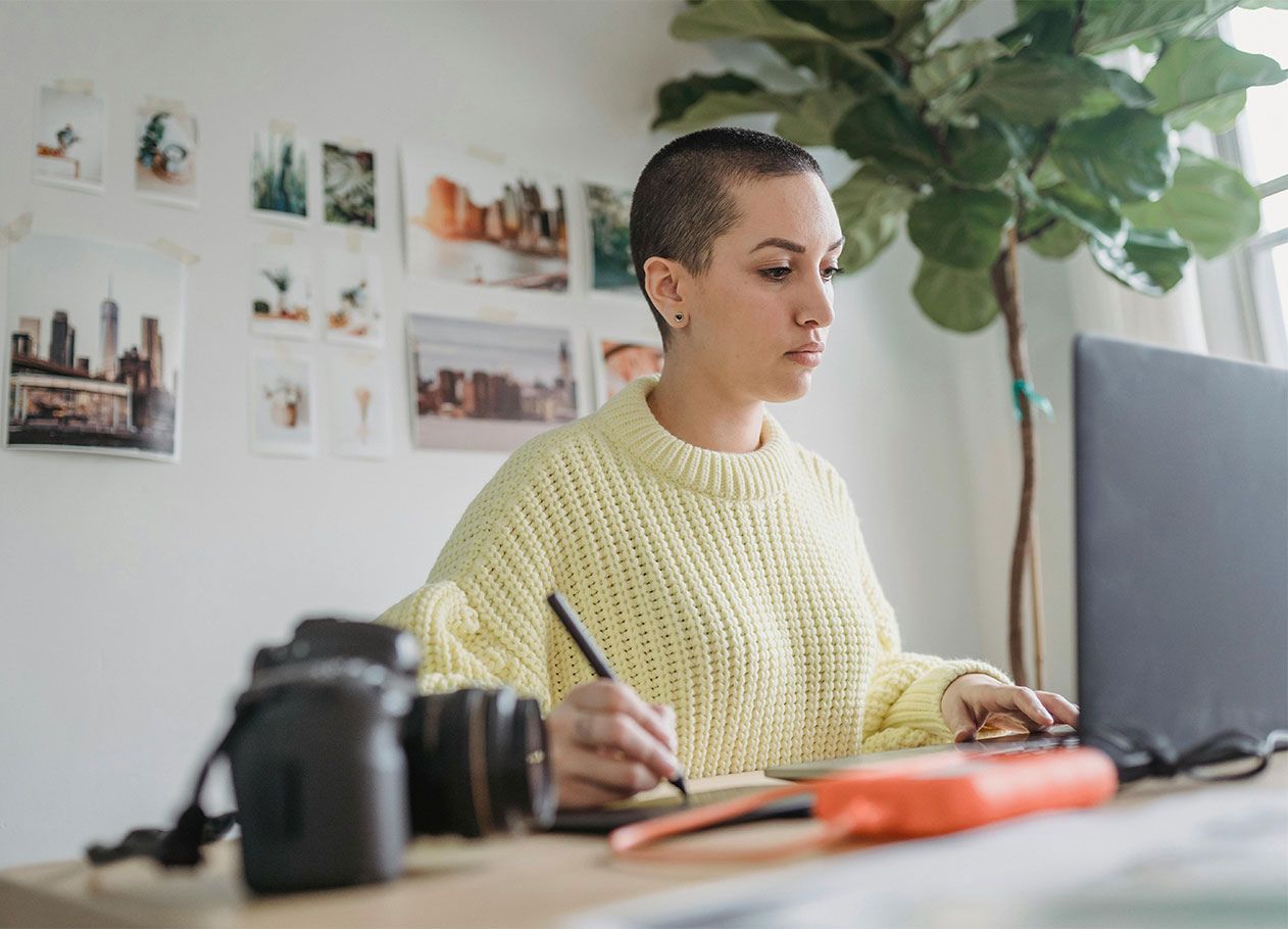 woman with shaved head working at laptop with camera set to the side