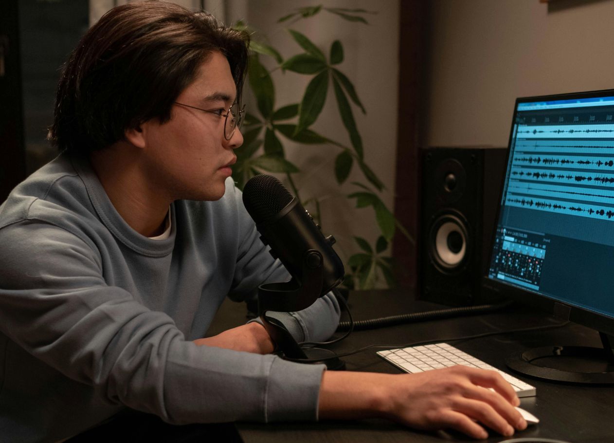 man wearing eyeglasses editing audio clips on desktop