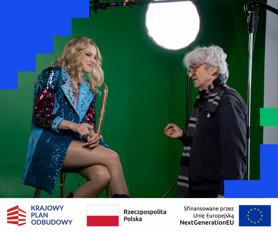 Kobieta w błyszczącym niebieskim płaszczu siedzi na krześle, rozmawiając ze starszym mężczyzną w okularach i szaliku na zielonym tle studia.