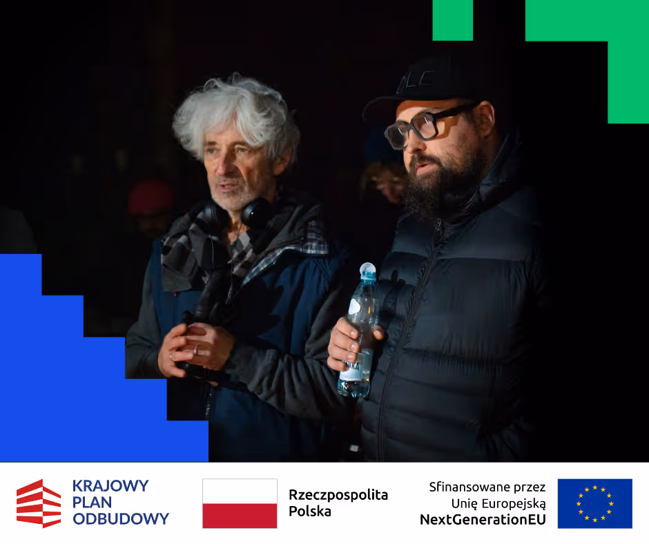 Dwóch mężczyzn w ciemnym otoczeniu, jeden z siwymi włosami i słuchawkami na szyi, drugi z brodą, okularami i czapką, trzymający butelkę wody.