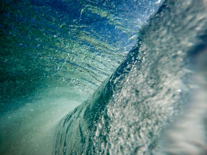 Close-up view inside a curling ocean wave showing water texture and bubbles.