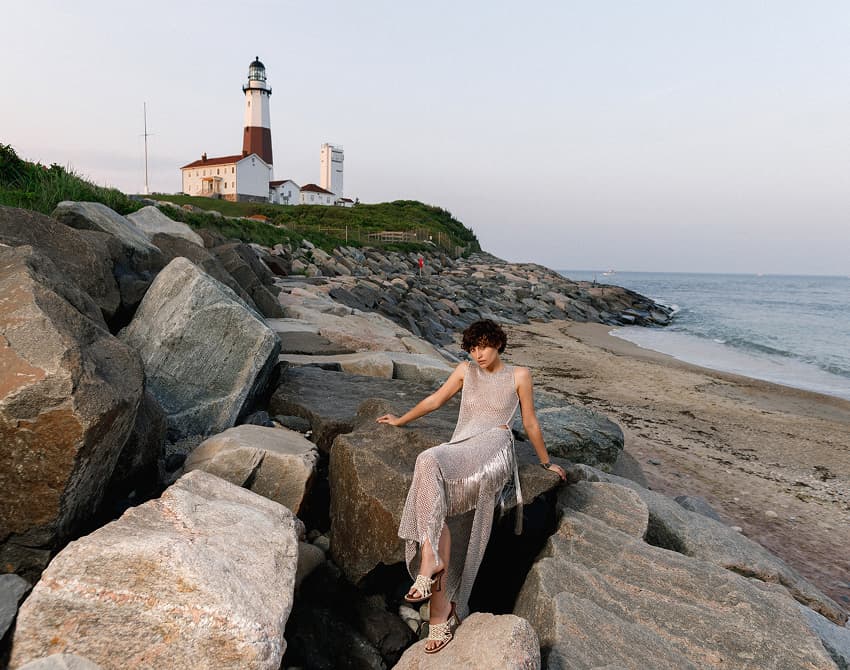 Fashion model on rocky beach near a lighthouse, editorial fashion photography for Social Life Magazine.