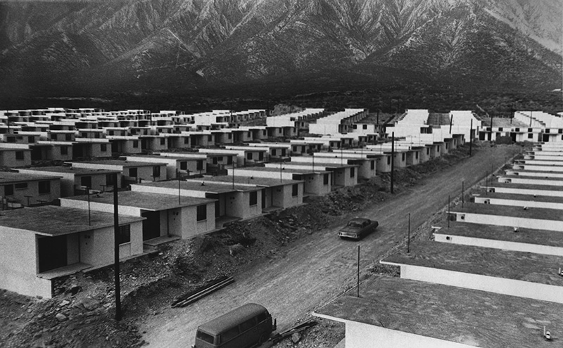 Hileras de casas en obra en la Huasteca, con terracería y la sierra detrás.