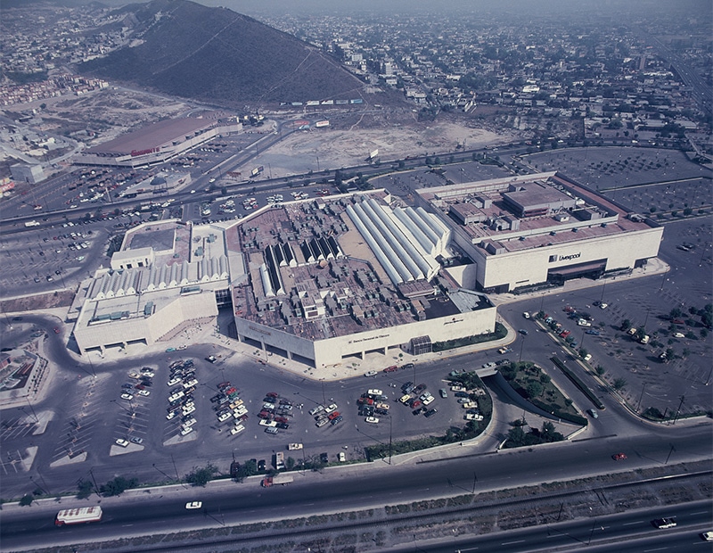 Vista aérea de Galerías Monterrey, rodeado de estacionamientos y una autopista.