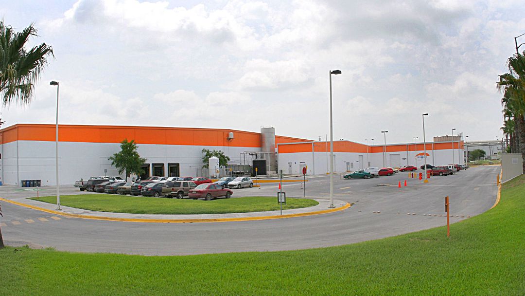 Nave de Bonafont con franja naranja, estacionamiento y palmeras.