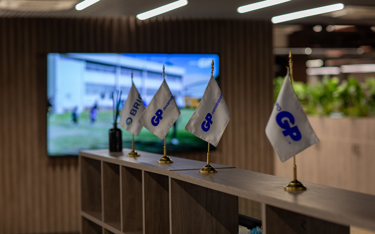 Banderines de GP y Brio sobre un mueble, frente a una pantalla de la oficina.
