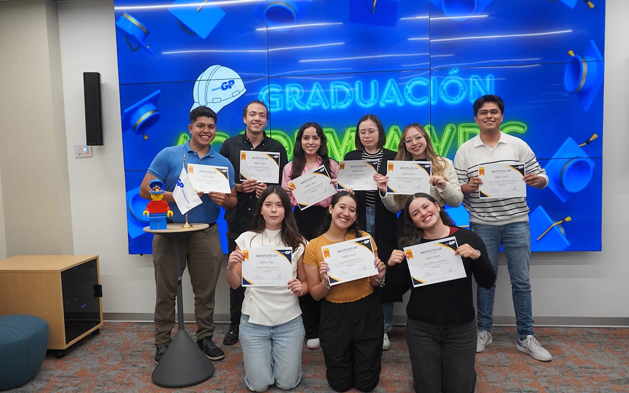 Ocho jóvenes sostienen certificados de graduación en dos filas dentro de una sala moderna, con una pantalla azul al fondo que muestra la palabra 'GRADUACIÓN' y varios birretes de graduación flotando.