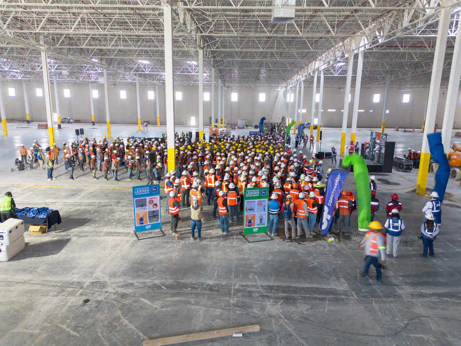 Trabajadores reunidos en una nave junto a lonas informativas y un arco verde.