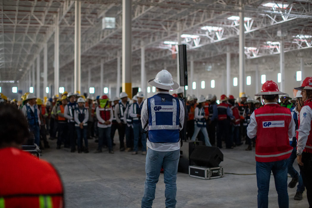Personal de GP, de espaldas, dirige una reunión de cuadrillas dentro de la nave.