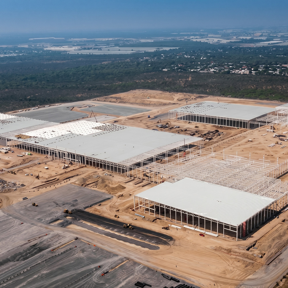Vista aérea de varias naves en obra, con cubiertas blancas y terreno de terracería.