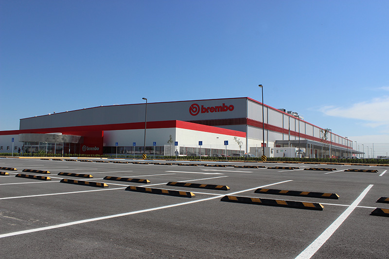 Planta Brembo en Tequila, de fachada roja y gris, con estacionamiento vacío.