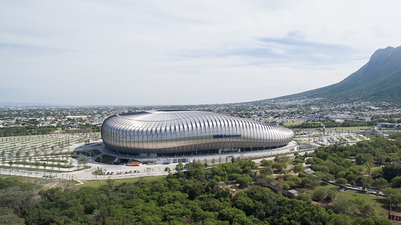 Vista aérea del Estadio BBVA, de cubierta plateada, con el cerro de fondo.