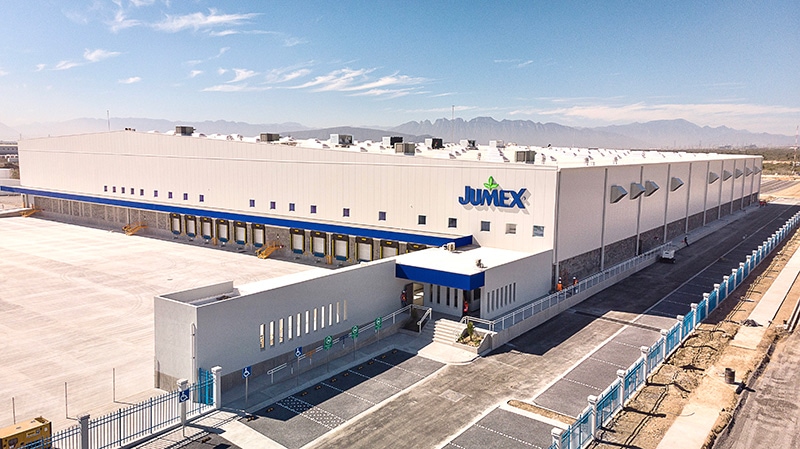 Centro de distribución Jumex, con andenes azules y montañas al fondo.