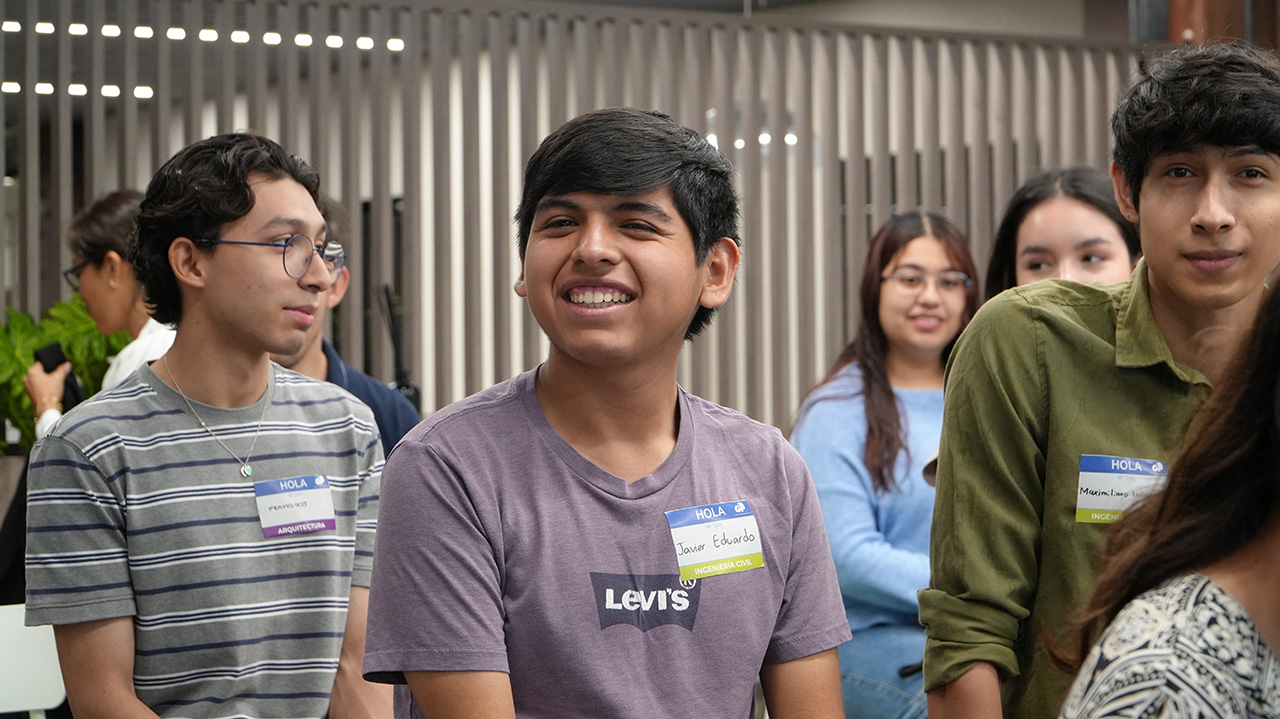 Jóvenes con gafete sonríen de pie durante un encuentro de la fundación.