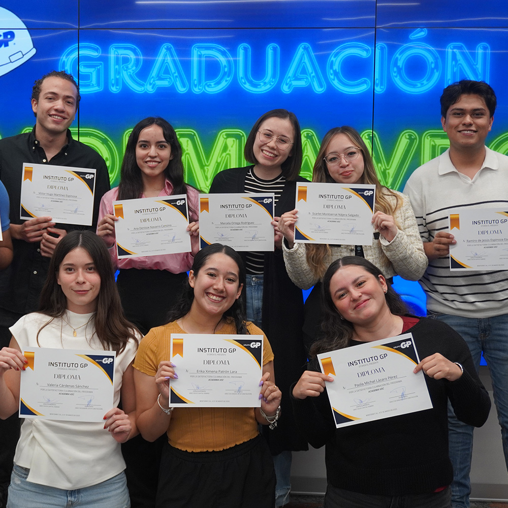 Egresados de Instituto GP muestran sus diplomas frente al letrero de graduación.