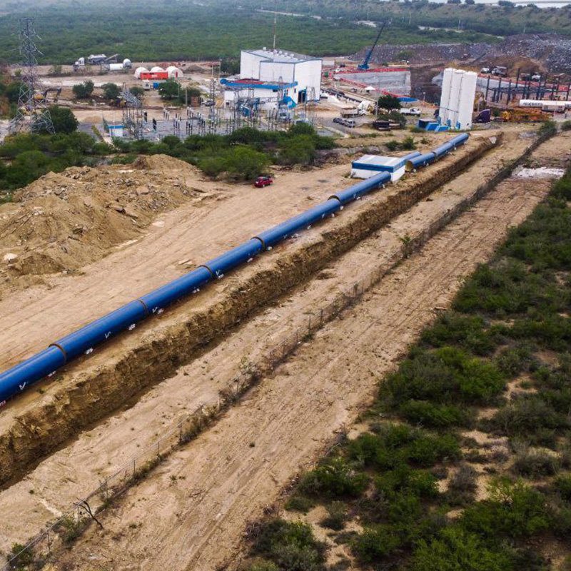 Tramo del Acueducto El Cuchillo con tubería azul, silos blancos y una grúa.