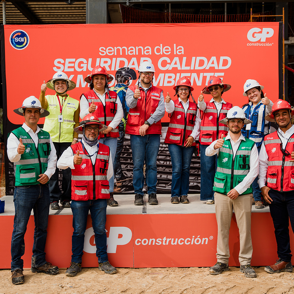 Equipo de GP en tarima, con cascos y chalecos, frente al letrero de la Semana de la Seguridad.