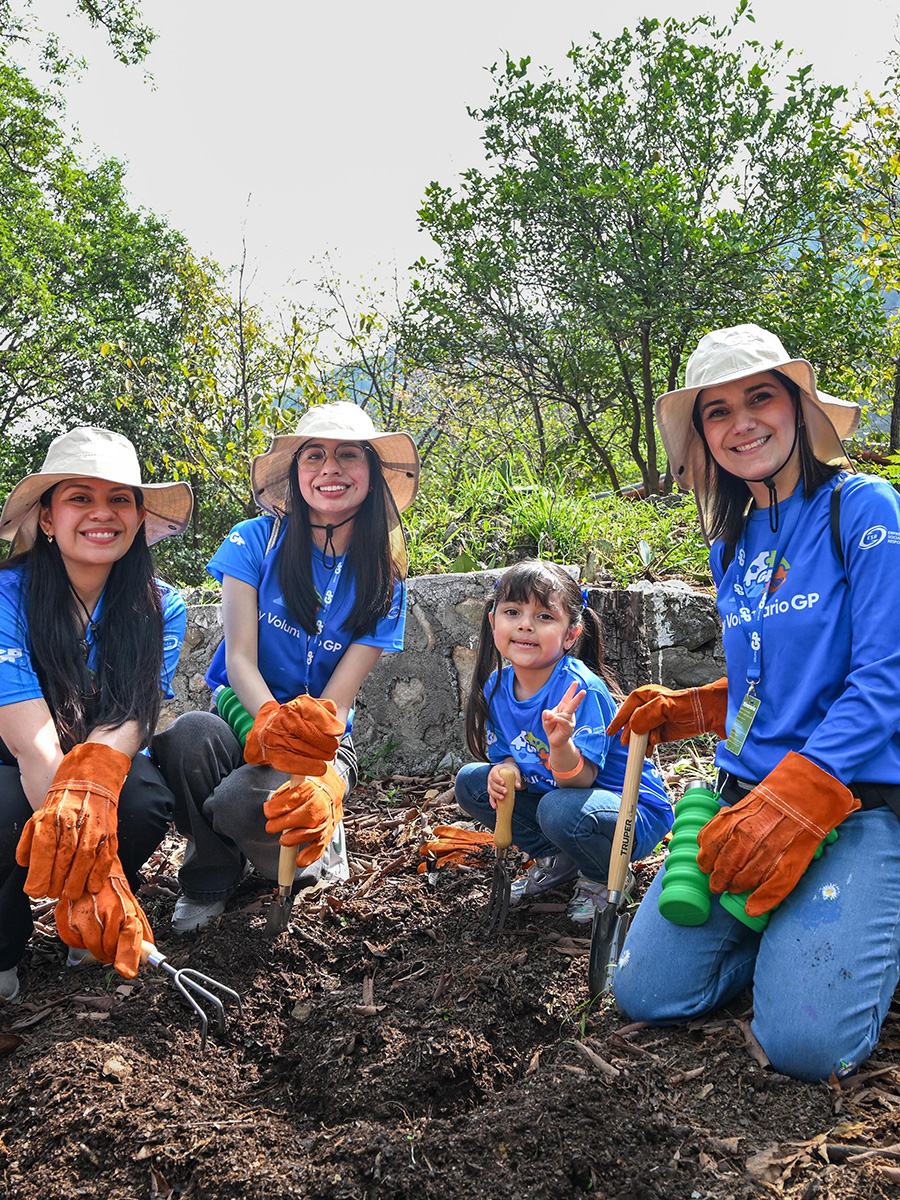 Three volunteers and a little girl are working the soil with shovels and a rake.