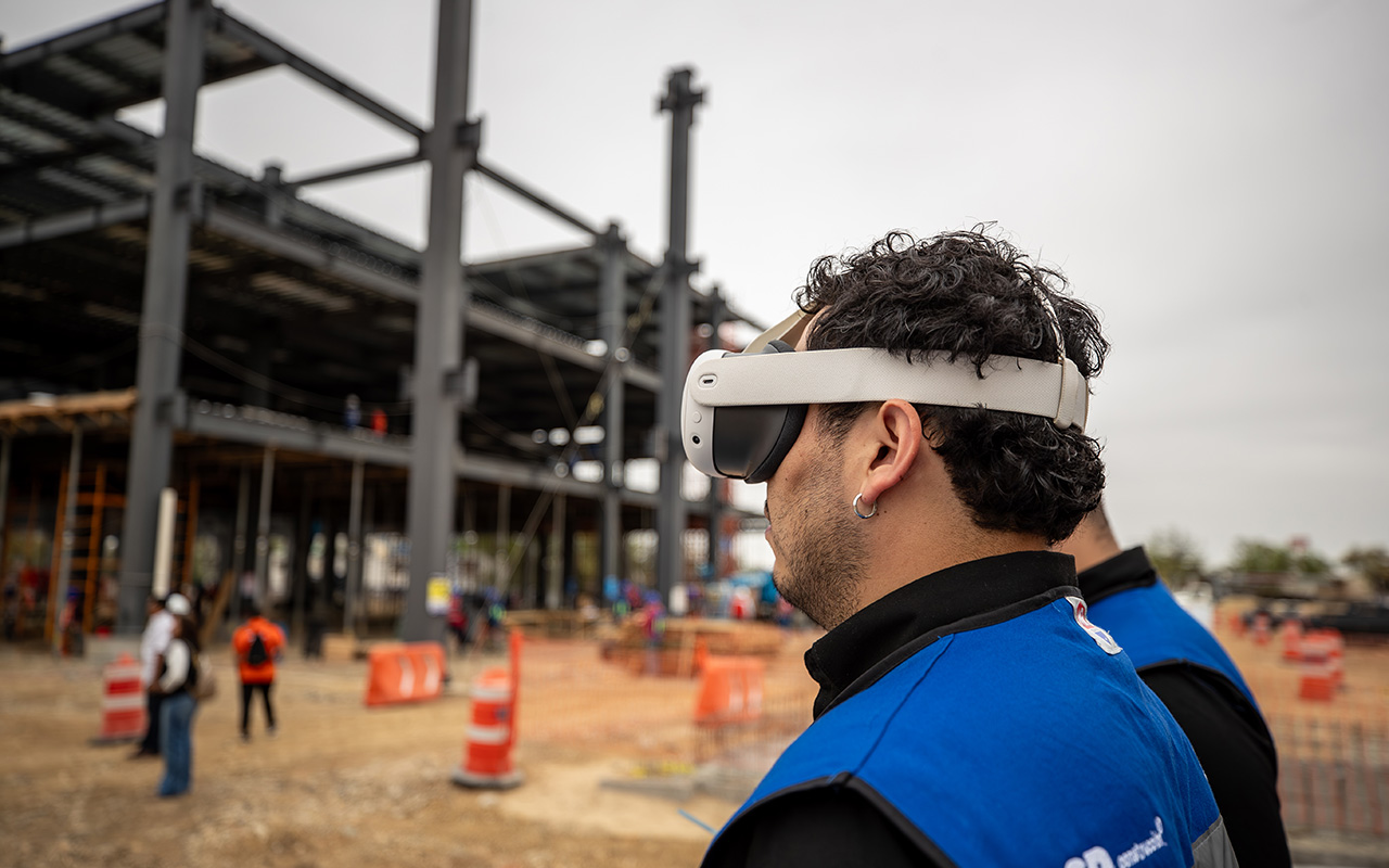 Colaborador con visor de realidad virtual observa la estructura de acero de una nave.