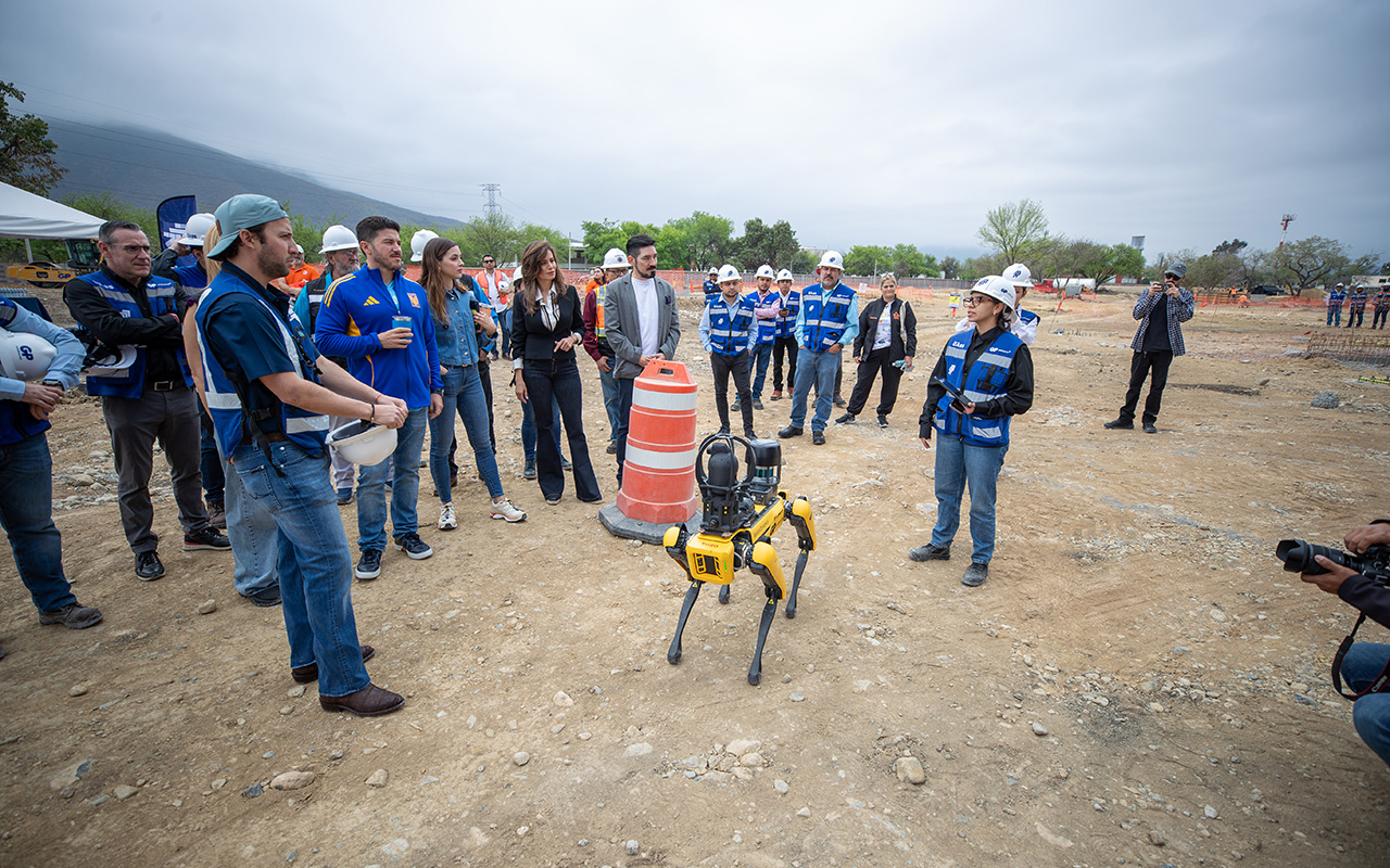 Demostración del robot cuadrúpedo amarillo en terreno de obra, con el equipo alrededor.
