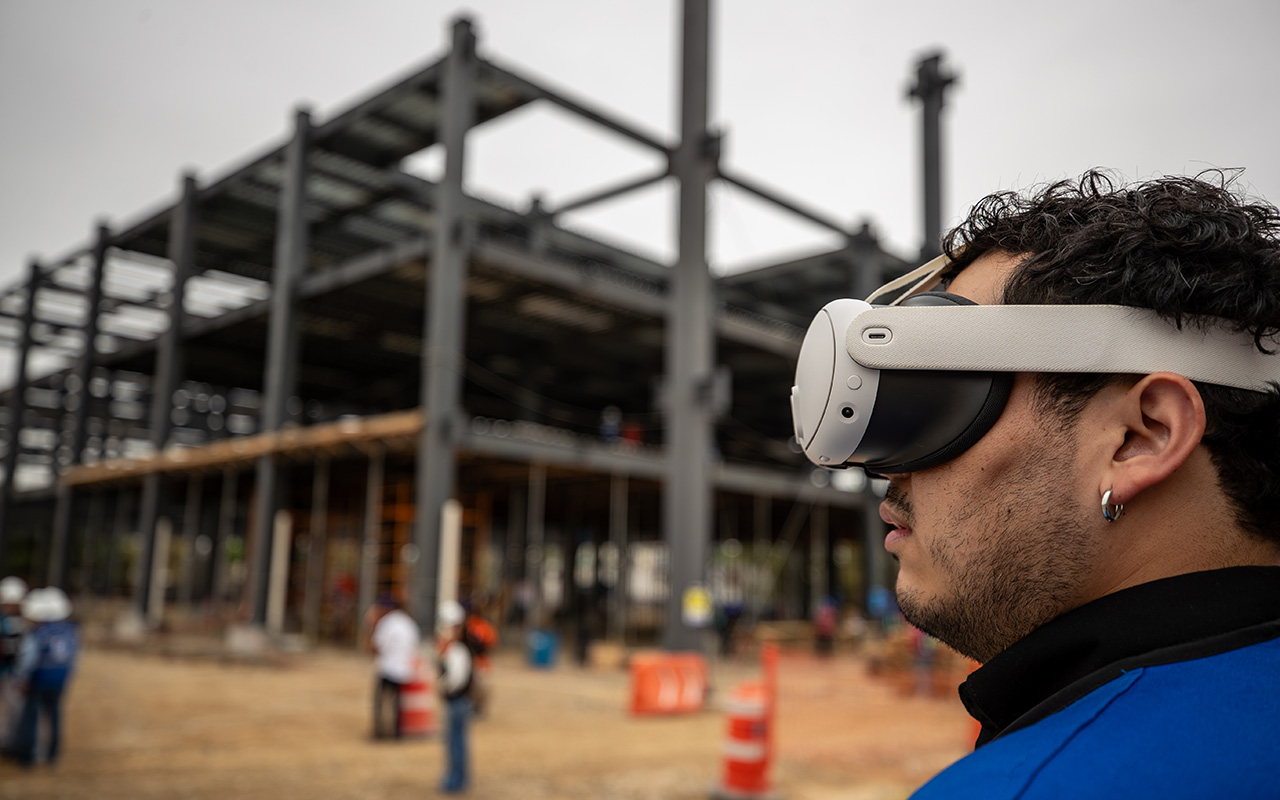 Primer plano de un colaborador con lentes y visor de realidad virtual frente a la estructura.